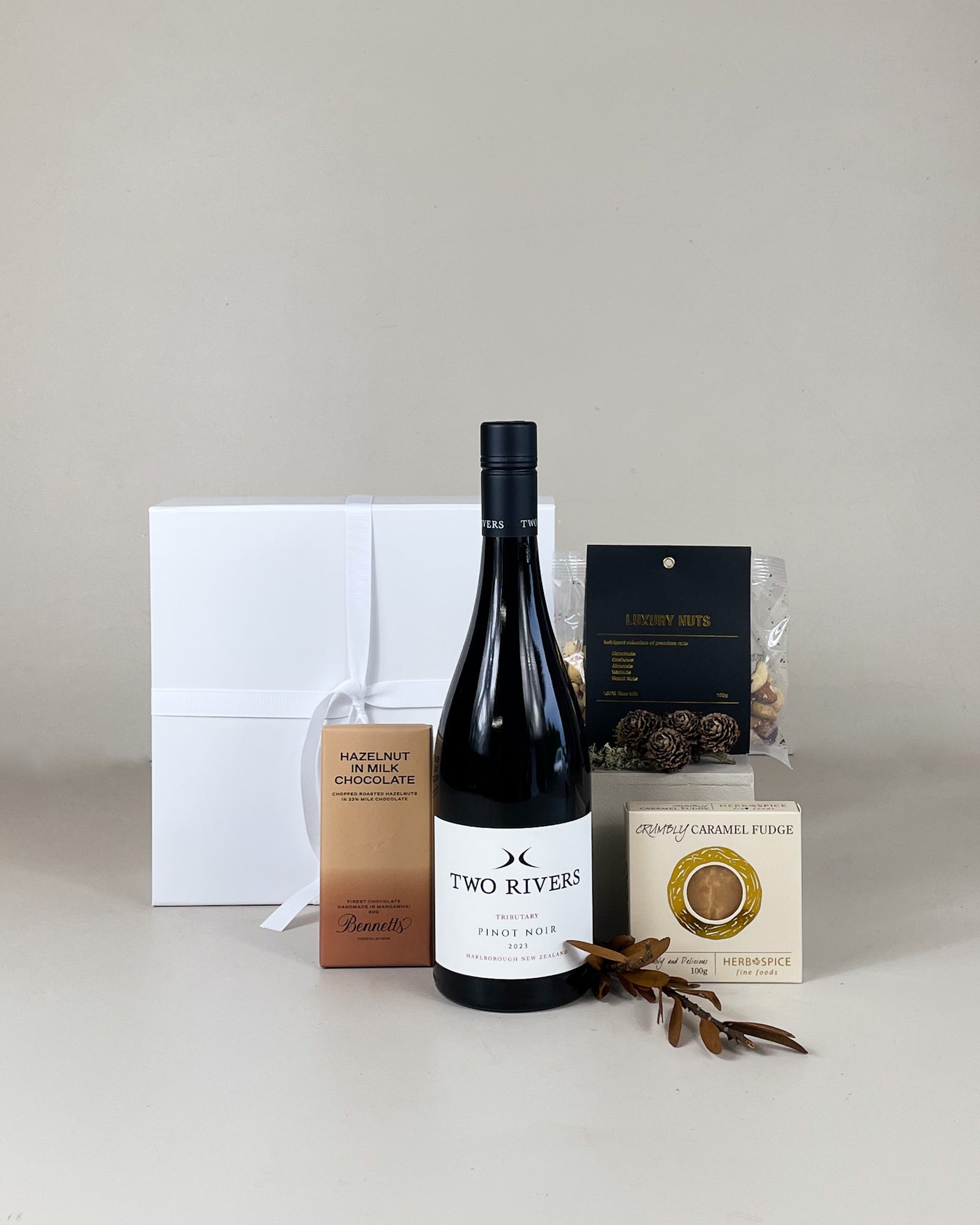 Drinks and nibbles gift set featuring assorted nuts, chocolate, and fudge, beautifully arranged for gifting.