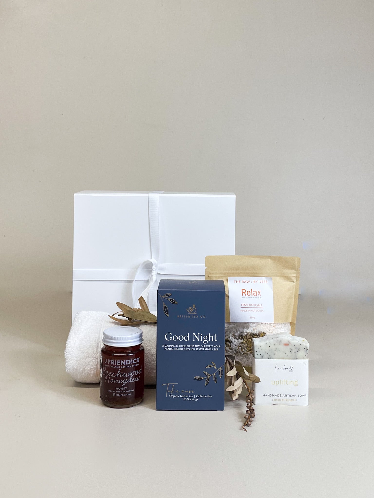 Relaxation gift box with herbal tea, honey, natural soap, lavender bath salts, ribbon-tied magnetic gift box, and handwritten gift card.