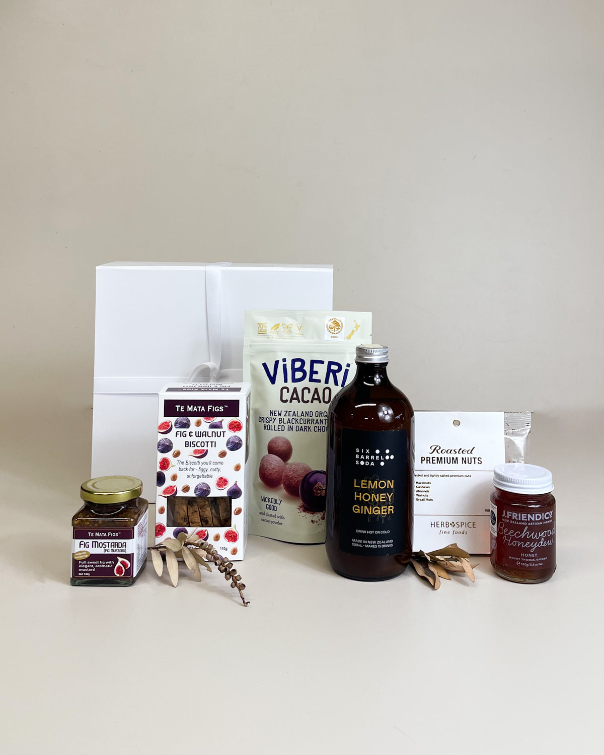 v\Wellness food gift box with lemon and honey soda syrup, blackcurrant fig relish, mixed nuts, fig and walnut biscotti, premium ribbon packaging, and handwritten gift card.
